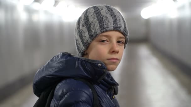 Portret van alleen zelfverzekerde jongen in hoed en jas in ondergrondse overdekte loopbrug in de stad in de winter — Stockvideo