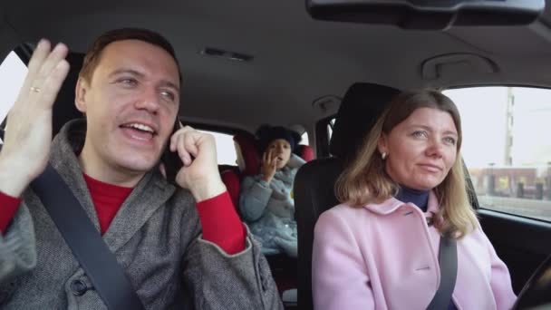 Married couple with children on trip. woman is driving car with excited man talk on phone about work — Vídeo de stock