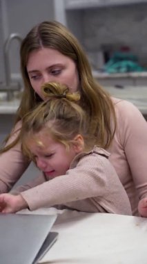 Disgruntled, irritated child knocks handles on mom laptop without letting her work