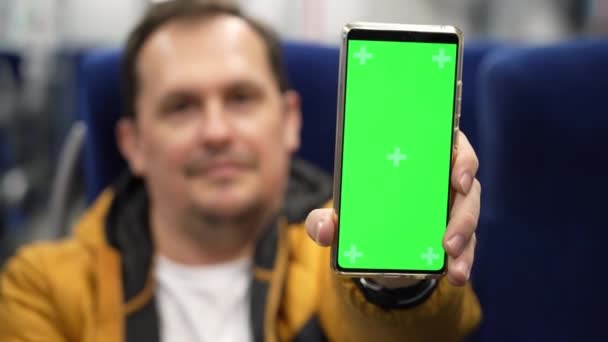 Hombre maduro paseo en tren y presenta teléfono con cromakey a la cámara, muestra billete electrónico, pasaporte covid — Vídeos de Stock