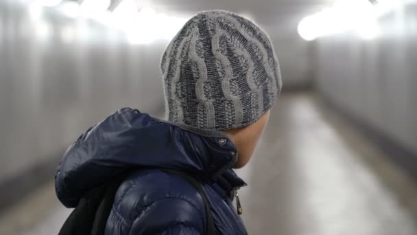 Портрет одинокого мальчика отвернулся от камеры в подземном переходе в городе — стоковое видео