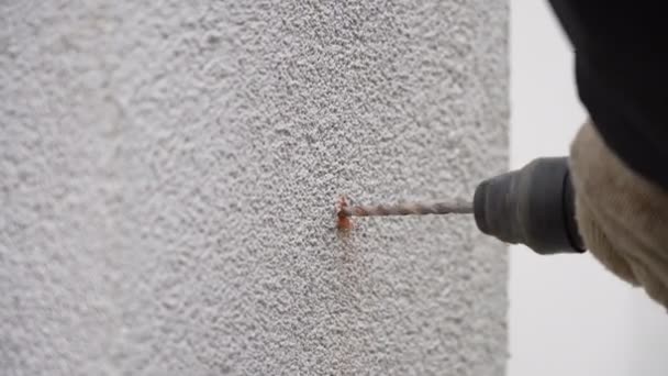Hole is drilled in stucco column outdoors. process of drilling with drill, red brick chips crumble — Stok video