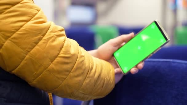 Вид ззаду чоловіка дивитися смартфон з зеленим екраном і перегляд онлайн в поїзді — стокове відео