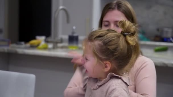 Crying girl interferes with the moms work on laptop. Woman tries to distract child from hysterics — Video