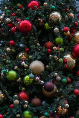 Dekoratif topları, oyuncakları ve parlak çelenkleri olan Noel ağacı dalını yakından izleyin. Noel ağacı süslemeleri, mücevherler ve sokak lambaları.