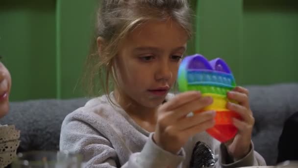 Дитяча дівчинка грає в барвистому іграшковому поп-музиці в кафе. Нова силіконова антистресова іграшка для дітей — стокове відео