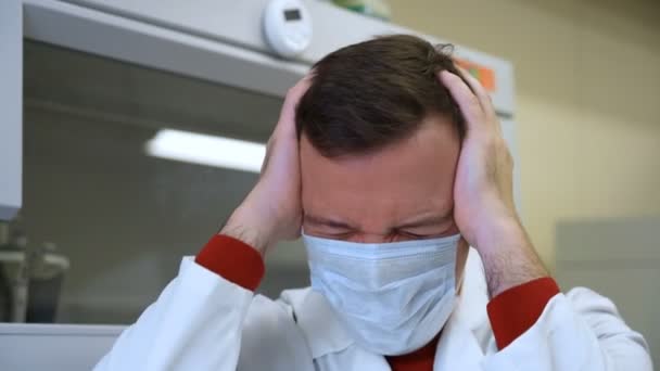 Millennial läkare lider av migrän huvudvärk problem att hålla huvudet med händerna eftersom stress i lab — Stockvideo