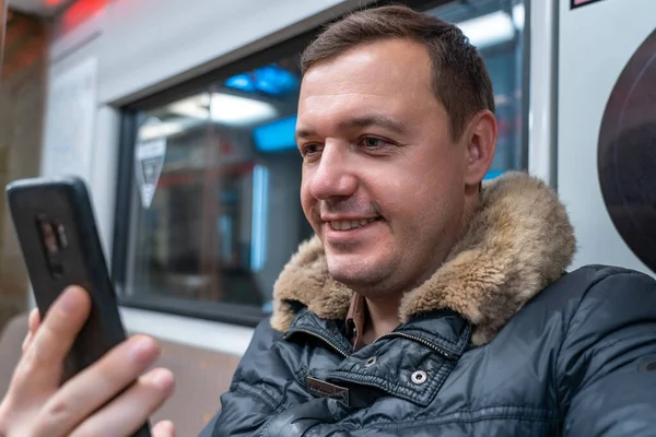 Profil porträtt av tusenåriga positiva killen ser sociala medier, sms: a meddelanden med mobiltelefon när du rider hem med tåg — Stockfoto