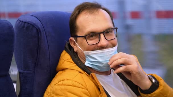 Heureux homme millénaire monte train et sourit à la caméra après avoir abaissé un masque médical sur son menton — Video