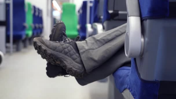 Le gambe dell'uomo penzolano e bloccano il passaggio del resto della gente nel treno in movimento — Video Stock