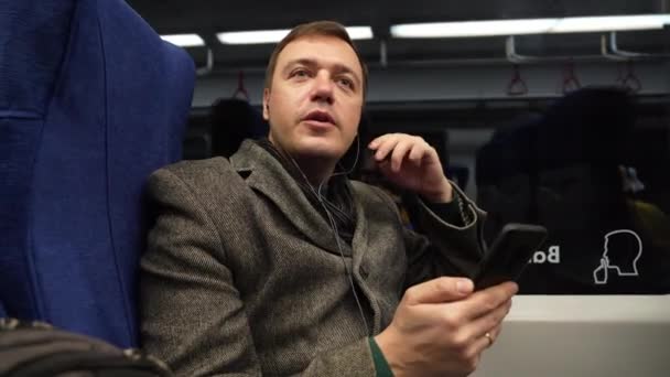 Maturo ragazzo in cappotto grigio cavalcando sul treno utilizzando il telefono cellulare discute i processi di lavoro su videocall — Video Stock