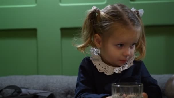 Petite fille danse et boit de la limonade douce fraîche du kiwi assis à table dans un café de la ville — Video