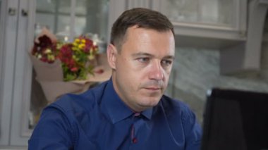 Genç erkek işçi ofis masasında oturan bilgisayarlı dizüstü bilgisayar kullanıyor.