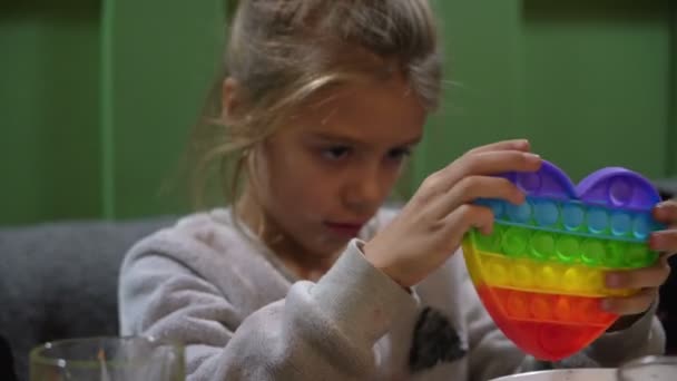 Grabben leker i färgglada anti-stress leksak popit på caféet. Ny silikonantistress leksak för barn — Stockvideo