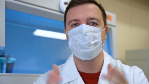 Впевнений лікар у масці розмовляє на камеру в лікарні — стокове відео