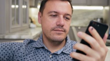 Adam mobil uygulama üzerinden video konferansında selamlaşıyor ve konuşuyor. Gülümseyen erkek aile ile tanışır