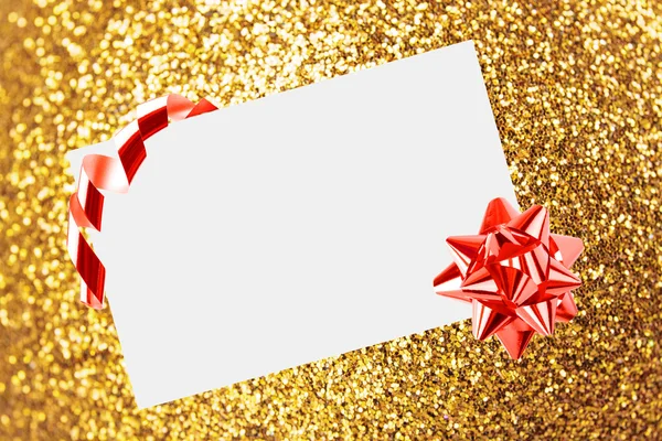 Vánoční list papíru s lukem a stuhami na žlutém rozostřeném pozadí — Stock fotografie