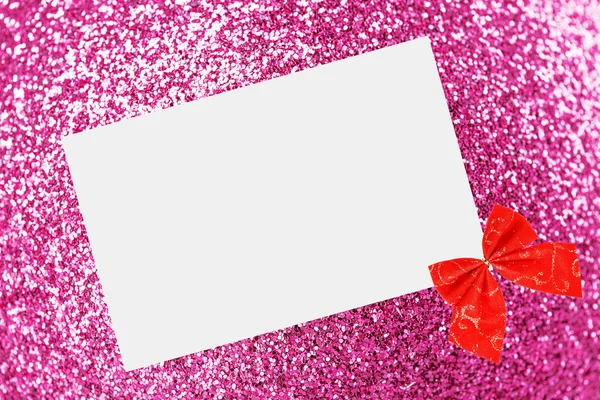 Christmas sheet of paper with bow and ribbons on pink defocused background — Stockfoto