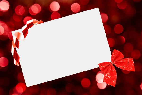 Foglio di Natale di carta con fiocco e nastri su sfondo rosso sfocato — Foto Stock