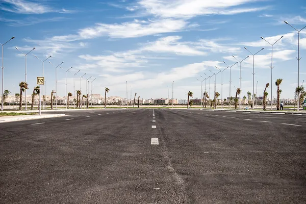 Strada asfaltata vuota con cielo nuvoloso e luce solare — Foto Stock