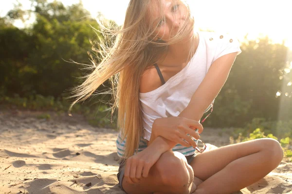 Chica sentada cerca del río contra el sol — Foto de Stock