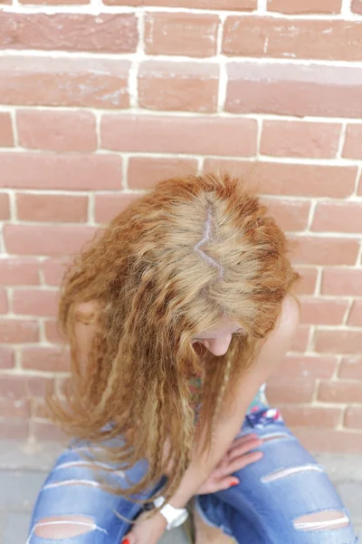 Beautiful woman with long blond hair standing against brick-wall — Stock Photo, Image