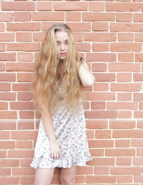 Attraente giovane bionda sullo sfondo di un muro di mattoni . — Foto Stock