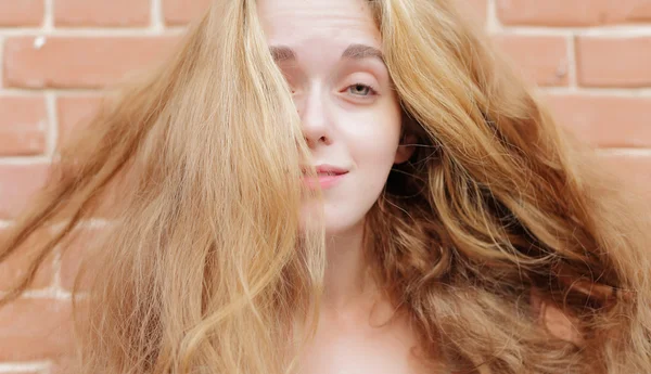 Atractiva rubia joven en el fondo de una pared de ladrillo . —  Fotos de Stock