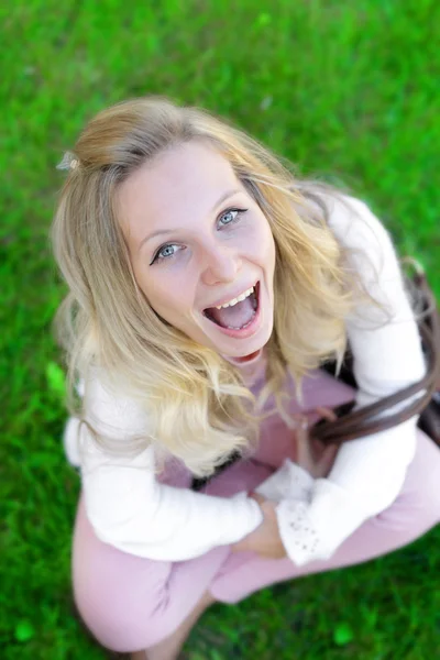 Carefree woman sitting in a green field — Stock Photo, Image