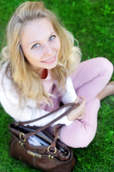 Zorgeloos vrouw zitten in een groen veld — Stockfoto