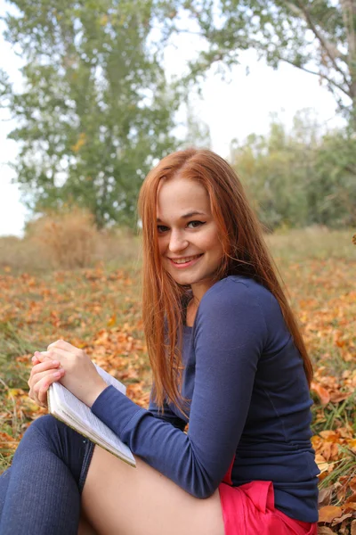 Молодая, красивая девушка, держащая открытую книгу, читает — стоковое фото