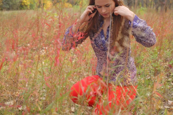 Schöne Frau steht im Herbst in einem Park — Stockfoto