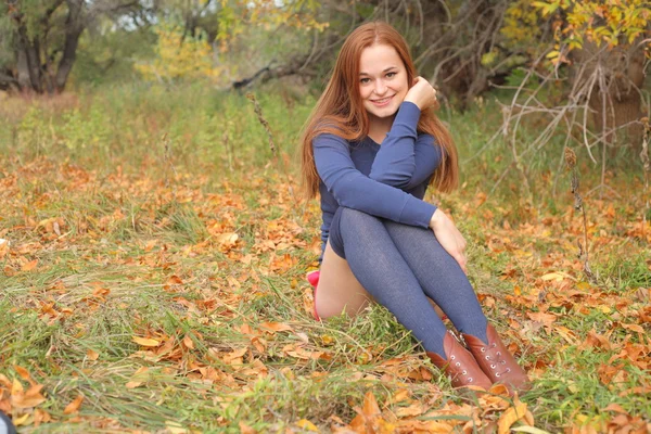 Retrato de uma bela mulher ruiva sentada na grama — Fotografia de Stock