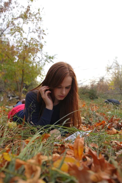 Redhead young university student studying lying down in grass — Stock Photo, Image