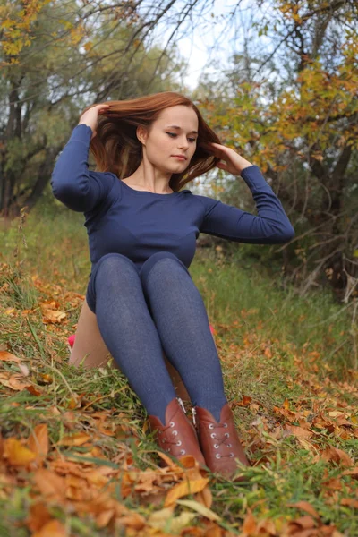 Portret van een mooie roodharige vrouw zittend op het gras — Stockfoto