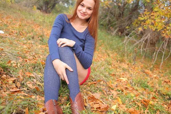 Retrato de uma bela mulher ruiva sentada na grama — Fotografia de Stock