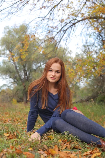 Portrait of a beautiful red-haired woman sitting on the grass — Stock Photo, Image