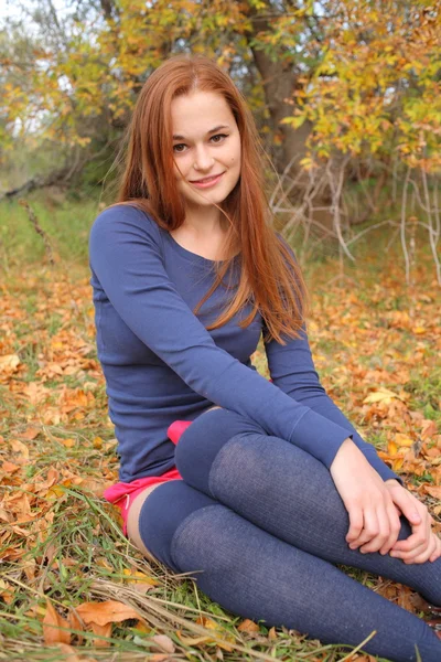 Porträt einer schönen rothaarigen Frau, die im Gras sitzt — Stockfoto