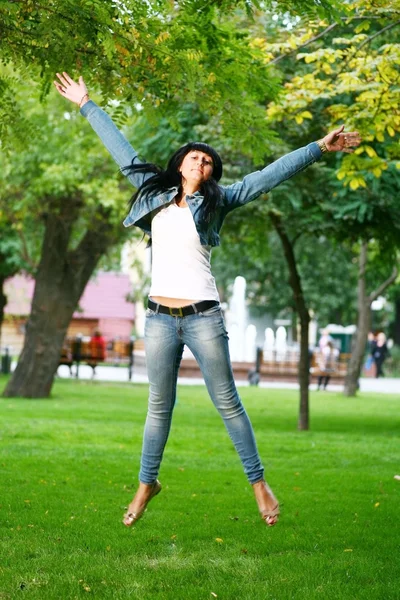 Jonge vrouw jamping op een gras — Stockfoto