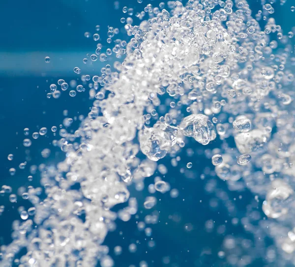 Gotas de agua cayendo sobre fondo azul — Foto de Stock