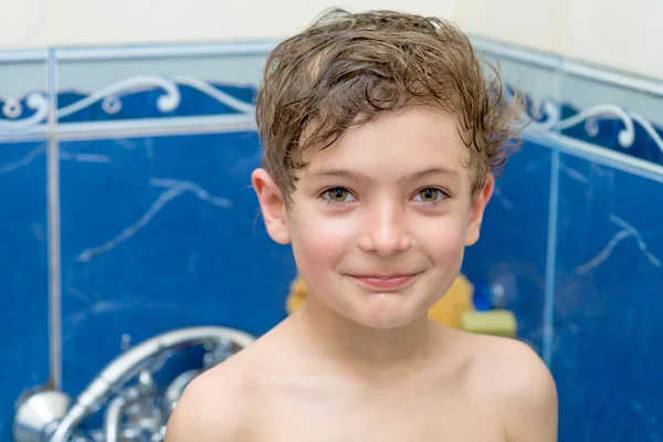 Petit garçon souriant dans la salle de bain contre un mur bleu — Photo