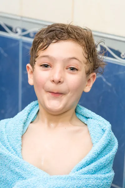 Petit garçon souriant dans la salle de bain contre un mur bleu — Photo