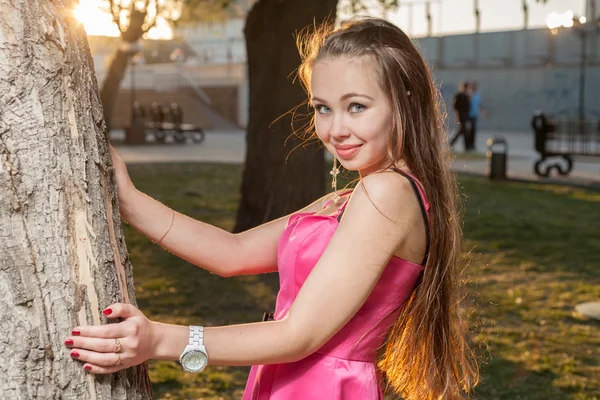 Chica en retroiluminación al atardecer cerca del árbol — Foto de Stock