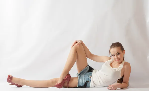 Glimlachend blonde vrouw shirt en spijkerbroek korte broeken liggend — Stockfoto