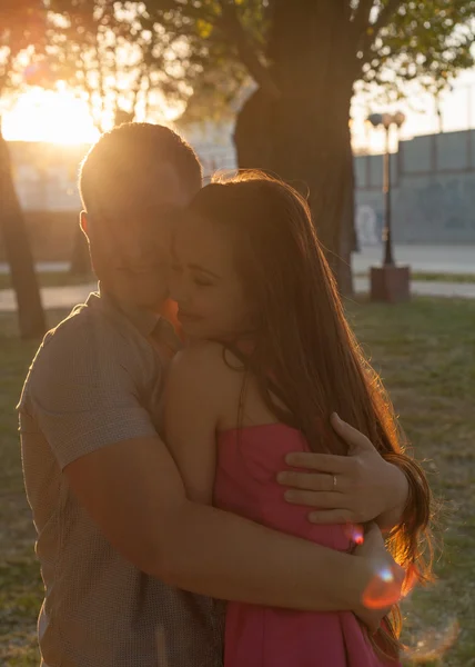 Casal em retroiluminado ao pôr do sol no parque — Fotografia de Stock