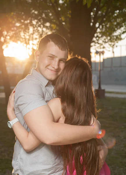 Casal em retroiluminado ao pôr do sol no parque — Fotografia de Stock