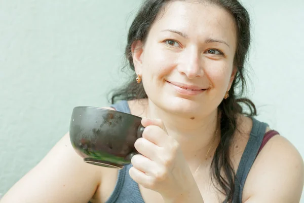 Женщина улыбается, пьет чай в помещении — стоковое фото