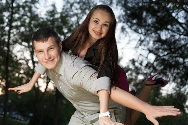 Ungt par åka snålskjuts i park — Stockfoto