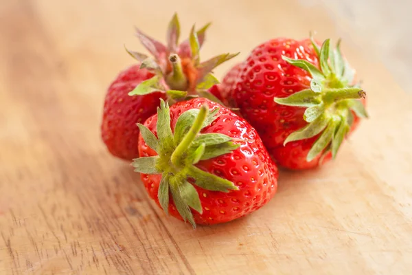 Drei Erdbeeren auf Holztisch — Stockfoto