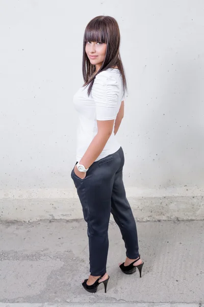 Pretty girl standing in front of wall — Stock Photo, Image